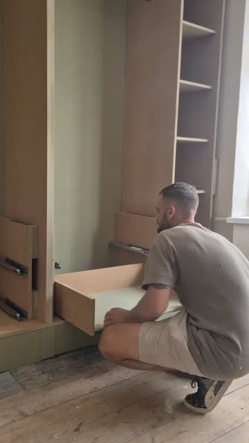 Person fitting a drawer into tall cabinetry.